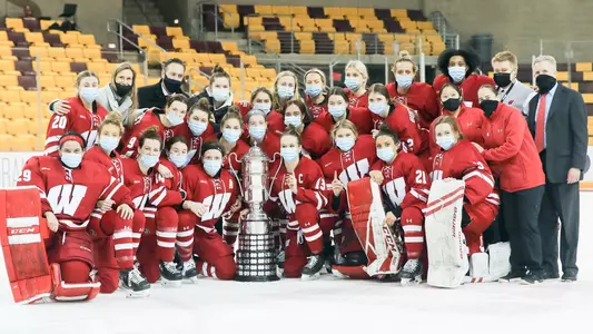 Women's hockey poses with trophy after winning 2021 WCHA regular-season title