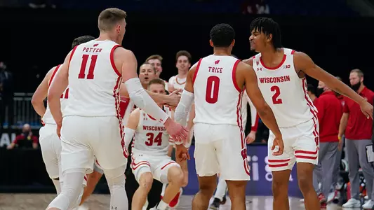 men's basketball team - Micah Potter, D'Mitrik Trice, Aleem Ford and team huddle at 2021 Big Ten men's basketball tournament against Penn State