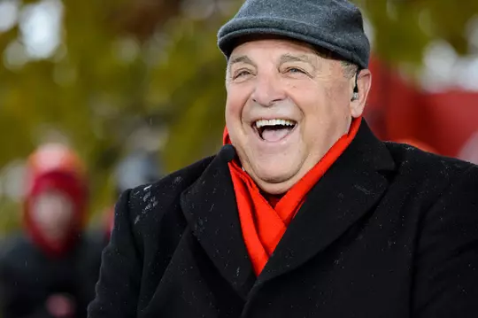 As cold rain falls and Wisconsin Badger and Michigan Wolverine fans wave signs and cheer in the background, Wisconsin Athletic Director Barry Alvarez talks with ESPN College GameDay commentators during a live broadcast of the show on Bascom Hill at the University of Wisconsin-Madison on Nov. 18, 2017. Immediately after the show, the Badgers play Michigan in a football game at Camp Randall Stadium. (Photo by Jeff Miller / UW-Madison)