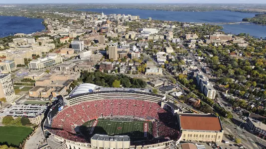 A sea of red-attired fans fill Camp Randall Stadium at the University of Wisconsin-Madison as the Wisconsin Badgers play the Northwestern Wildcats during a football game on Oct. 12, 2013. In the background, left to right, is Lake Mendota, the downtown Madison isthmus and Lake Monona. The aerial photograph of campus was made from a helicopter looking east during autumn. Wisconsin won the Homecoming game, 35-6, before a crowd of 81,411 people. (Photo by Jeff Miller/UW-Madison)