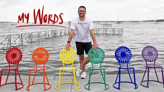 Marc Vandewettering, Wisconsin men's basketball director of operations, at the UW Memorial Terrace with rainbow terrace chairs. "My Words" is included with the photo.