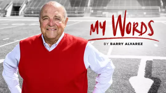 Barry Alvarez, Wisconsin director of athletics, standing on the football field inside Camp Randall Stadium. The text "My Words" is written over the image.