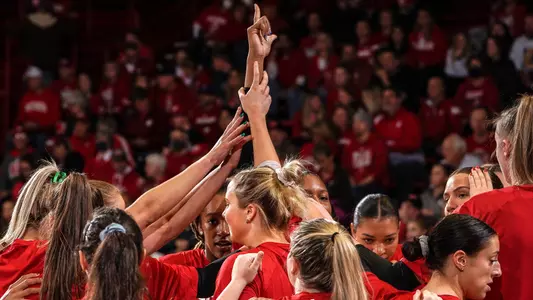 The Badgers huddle up on the court before a match with their hands raised.