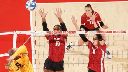 Devyn Robinson and Caroline Crawford go up for a block against a Michigan hitter.
