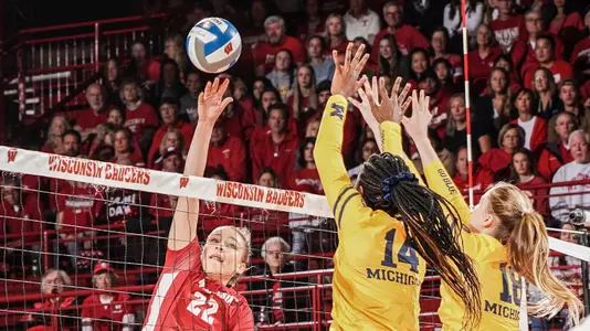 Julia Orzol hits against two Michigan blockers.