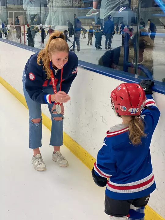 Jesse Compher, Wisconsin Women's Hockey, with USA Hockey jersey and Olympic silver medal greeting a small fan