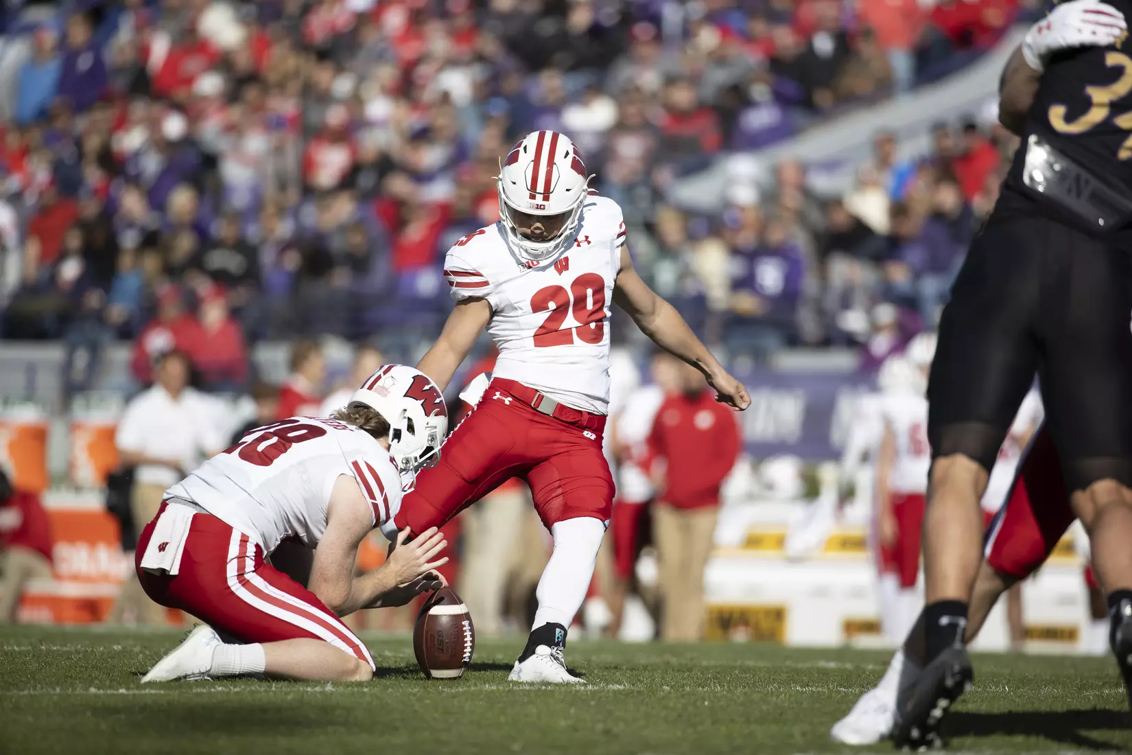 Wisconsin Badgers kicker Nate Van Zelst and punter Gavin Meyers (holding ball for kick) during an NCAA Big Ten Conference college football game against the Northwestern Wildcats on Saturday, Oct. 8, 2022, in Evanston, Ill. The Badgers defeated the Wildcats, 42-7.