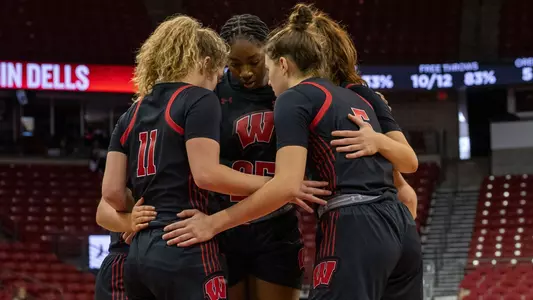 The women's basketball starting five in a huddle