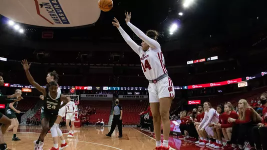 Krystyna Ellew shoots a 3-pointer in front of the Badger bench.