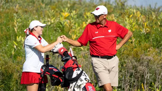 Wisconsin women's golf Emily Lauterbach and head coach Todd Oehrlein fist bump after a good score at the 2022 Badger Invitational at University Ridge Golf Course in Madison, Wisconsin on Tuesday, Sept. 20, 2022.