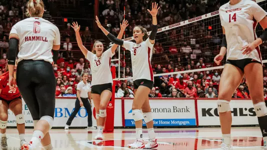 The Badgers raise their hands after winning a point on the court.