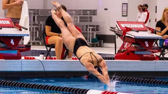 Abby Carlson dives in from the blocks for a swimming race.