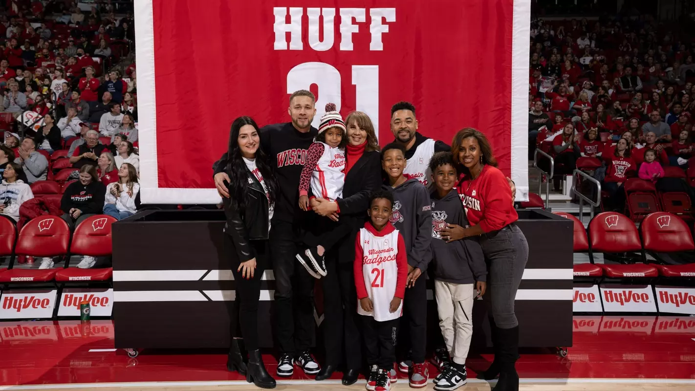 Theresa Huff and her family posing behind her No. 21 banner before it was raised into the rafters