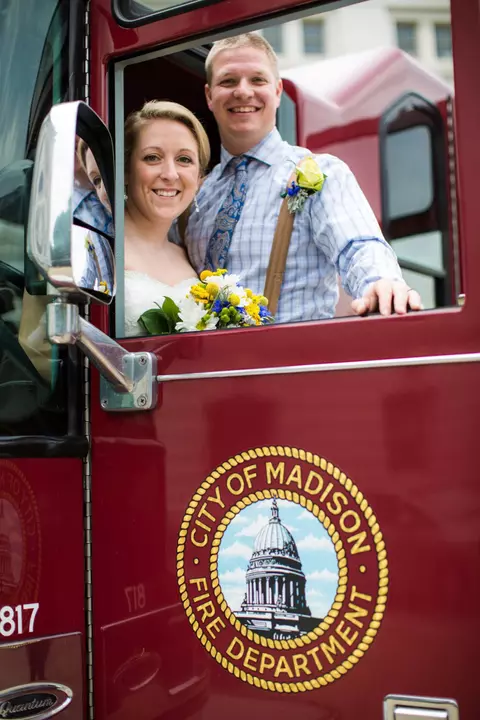 Sharon (Cole) Faust, Wisconsin women's hockey alumnus, and her husband Jesse smile on their wedding day on top of a firetruck