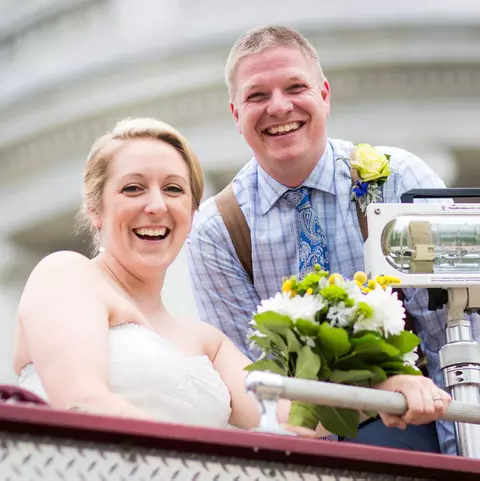 Sharon (Cole) Faust, Wisconsin women's hockey alumnus, and her husband Jesse smile on their wedding day on top of a firetruck