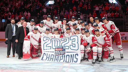 The Wisconsin men's hockey team poses with the 2023 Kwik Trip Holiday Face-Off trophy.
