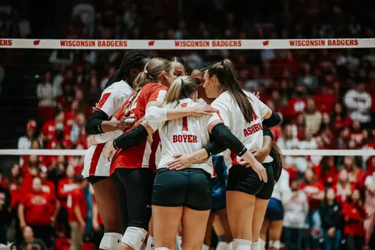 Wisconsin volleyball teammates huddle on court with Joslyn Boyer at center