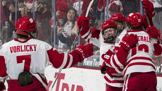 Members of the Wisconsin men's hockey team celebrate scoring a goal against Penn State.