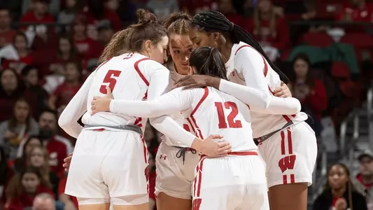 The starting five huddle on the court during a break in the game.