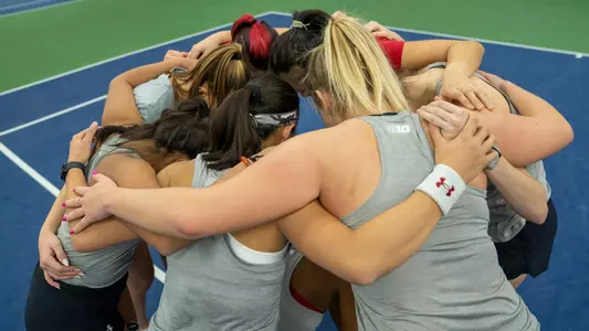 The women's tennis team in a huddle before a match