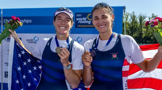 Sophia Vitas and her rowing partner Kristina Wagner holding American flags with a bronze medal around their necks during the medal ceremony at the 2023 World Rowing Championships.