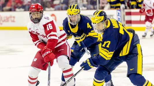 Tyson Dyck battles for the puck against two Michigan players.