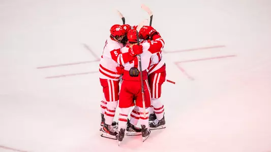 Members of the Wisconsin men's hockey team celebrate scoring a goal.