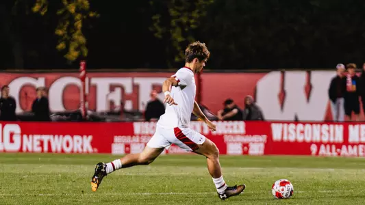 A soccer player kicks a ball forward
