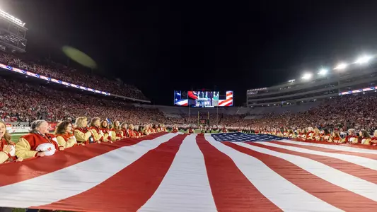 Wisconsin Badgers former women’s letter winners hold a giant flag during the National Anthem prior to a Big Ten Conference NCAA college football game against the Penn State Nittany Lions, Saturday, Oct. 26, 2024, in Madison, Wis. The Nittany Lions won 28-13. (Photo by David Stluka/Wisconsin Athletic Communications)