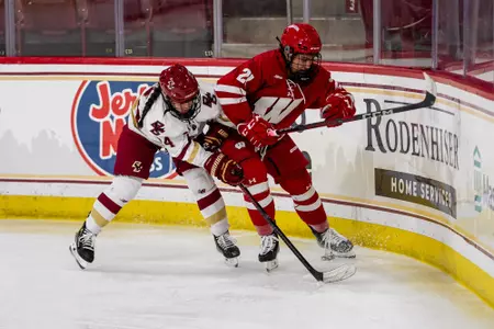 Emma Venusio battles against the boards for the puck in a game against Boston College