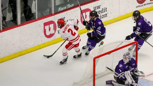 Finley McCarthy posses the puck behind the St. Thomas net against St. Thomas