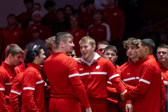 Shane Liegel is surrounded by teammates prior to his first wrestling dual match as a Badger