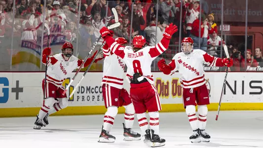 Members of the Wisconsin men's hockey team celebrate winning a game at the Kohl Center.
