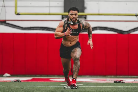 Chez Mellusi sprints with chains during winter speed training at the UW McClain Center indoor football field.