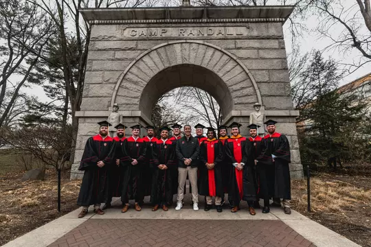 Wisconsin football head coach Luke Fickell stands with Wisconsin's 2023 winter senior class of student-athletes including Chez Mellusi