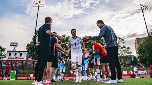 Men's soccer players walk onto the pitch before a game