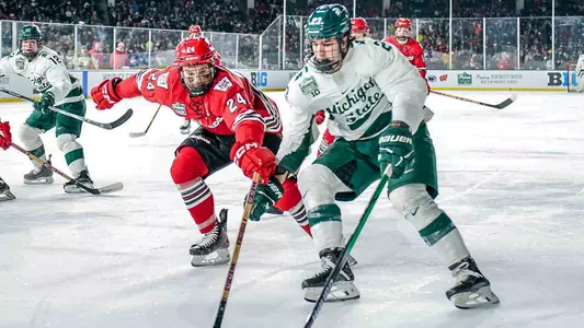 Anthony Kehrer battles for the puck against a Michigan State player at Wrigley Field