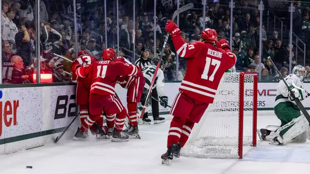 The Wisconsin men's hockey team celebrates an overtime victory at Michigan State