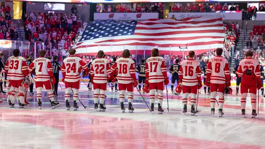 Badger men's hockey lines up behind a USA flag during the national anthem