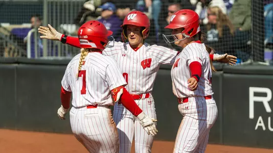 Badgers greet Kendra Lewis at the plate after homering at Northwestern