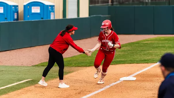 Jaclyn Showalter and head coach Yvette Healy high-five at third base against UT Arlington.