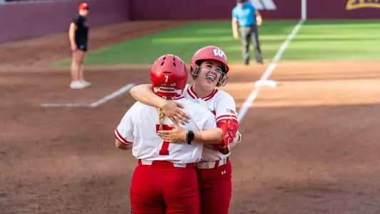 Hilary Blomberg and Kendra Lewis celebrate at home plate.