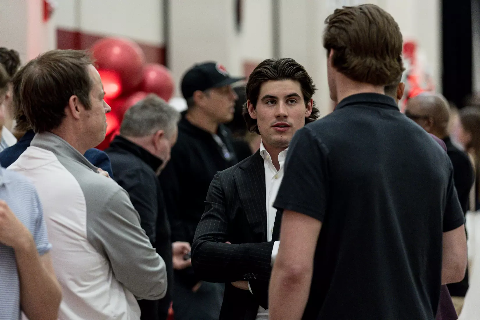 Men's hockey players talk with friends and family at Class of 2026 Student-Athlete Graduation Ceremony