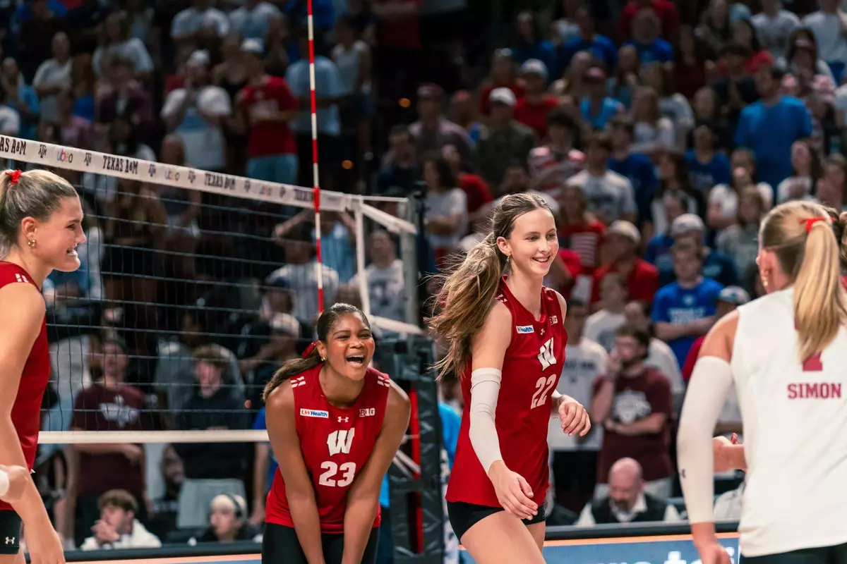 Wisconsin teammates Grace Lopez (#23) and Audrey Flanagan (#22) smile and celebrate near the net during a stoppage in play against Texas A&M.