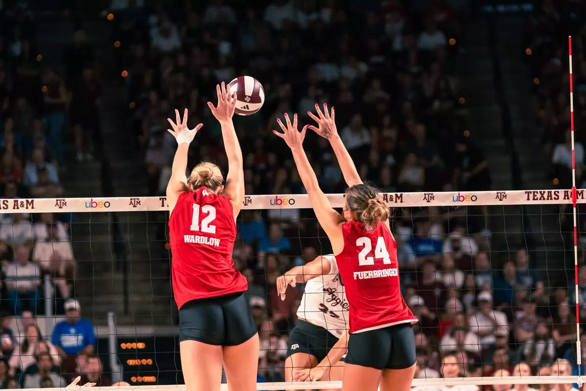 Wisconsin players Natalie Wardlow (#12) and Charlie Fuerbringer (#24) reach high above the net to form a two-person block against Texas A&M.