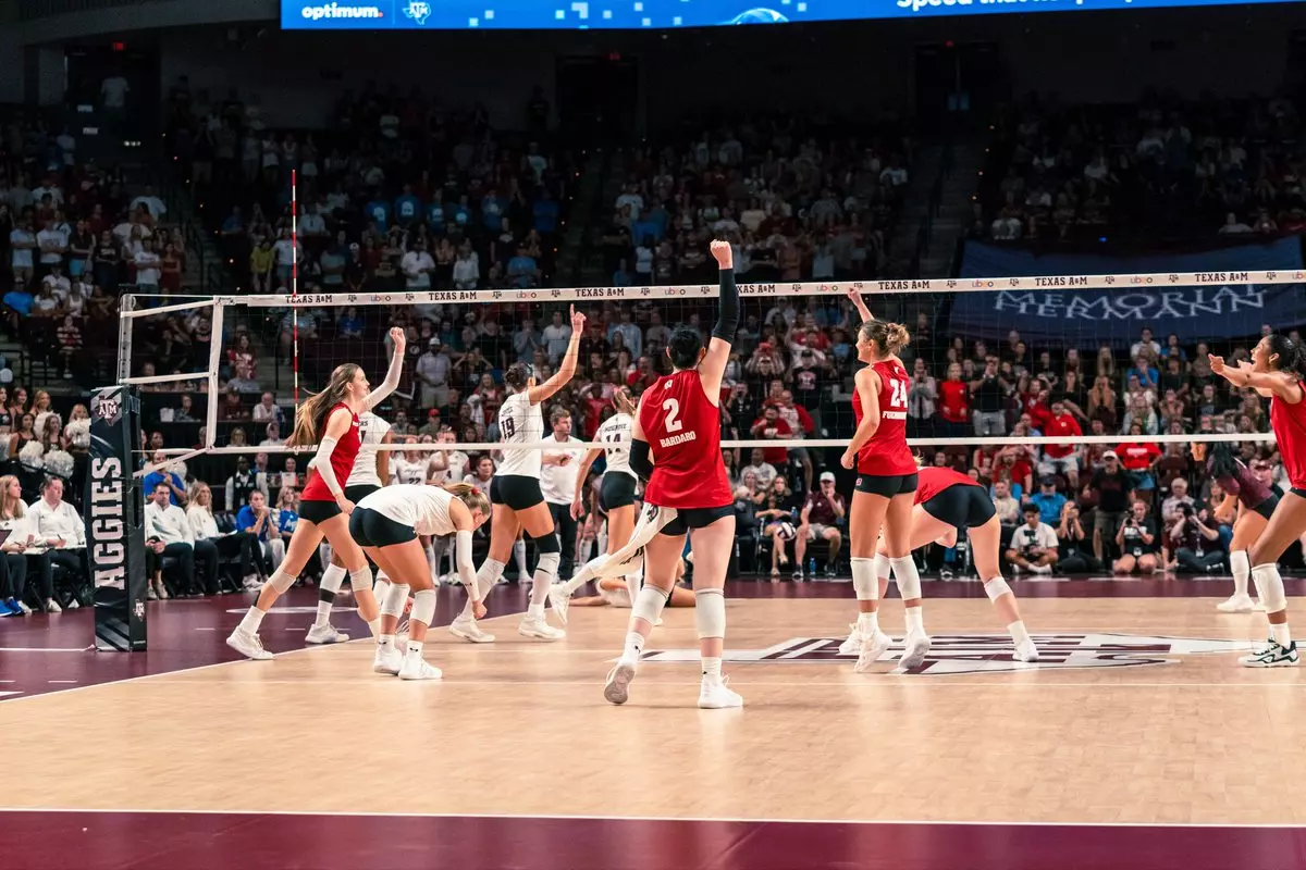 Anna Bardaro (#2) pumps her fist as Wisconsin volleyball players celebrate a point against Texas A&M near the net.