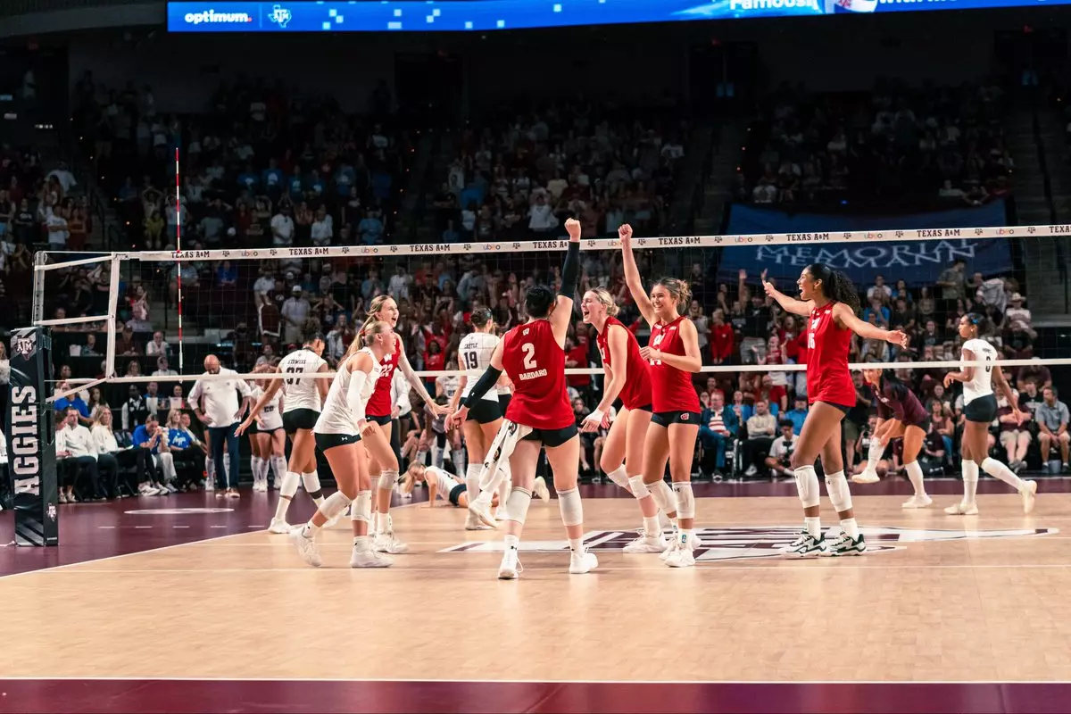 isconsin volleyball players, including Anna Bardaro (#2), Charlie Fuerbringer (#24), and Decelise Champion (#16), celebrate on the court with raised arms after scoring a point against Texas A&M.
