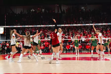 Anna Bardaro raises one arm as Wisconsin players celebrate a point against Oregon.