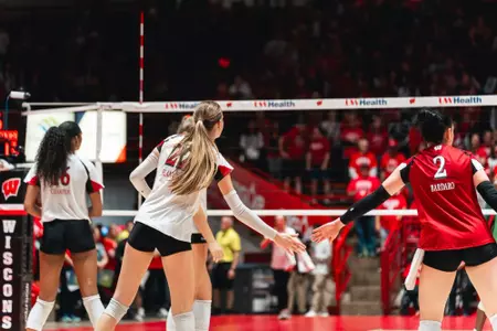 Audrey Flanagan reaches to exchange a low five with Anna Bardaro during Wisconsin’s match against Oregon.