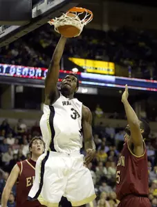 Eric Williams dunks as Elon's Gamble and Wyatt look on.